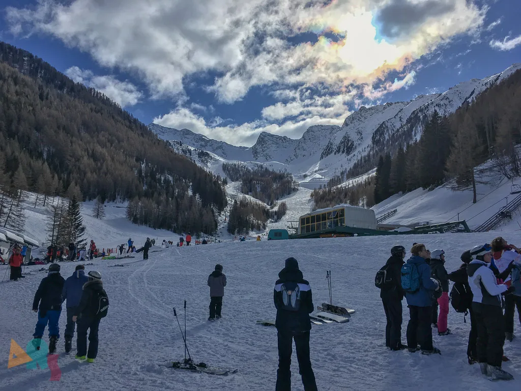 Blick über die Piste auf die Berge unter Wolken.
